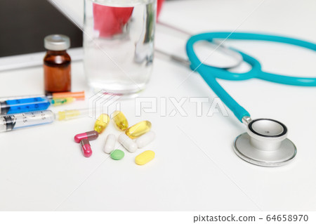 Pills and medical equiupments with vaccine, syringe and stethoscope on table. Pills and medical equiupments with vaccine, syringe and stethoscope on table. 64658970