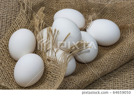 White chicken eggs wrapped in burlap next to a White chicken eggs wrapped in burlap next to a 64659050