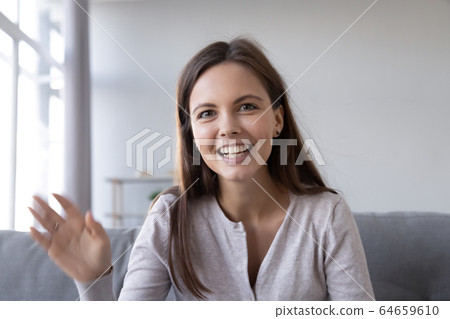 Happy teen girl waving hand saying hello looking at webcam Happy teen girl waving hand saying hello looking at webcam 64659610