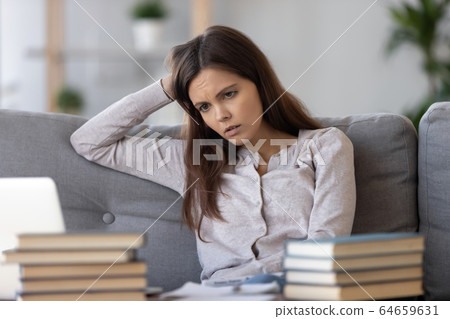 Tired bored teen looking at books stressed by exam preparation Tired bored teen looking at books stressed by exam preparation 64659631