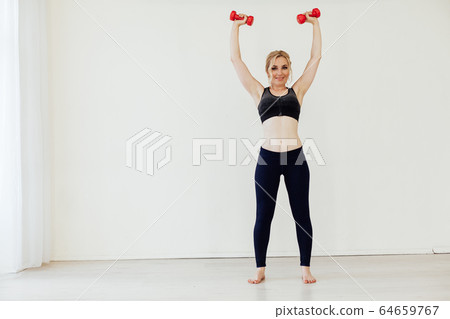 Beautiful blonde sports with dumbbells in fitness hall Beautiful blonde sports with dumbbells in fitness hall 64659767