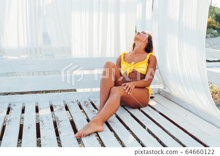 tanned woman in yellow swimsuit white tent tanned woman in yellow swimsuit white tent 64660122