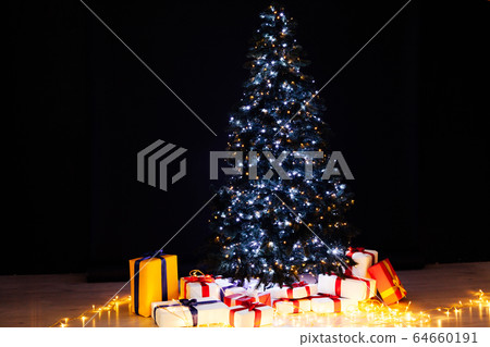 Christmas tree with gifts lights garlands for the new year on a black background 64660191