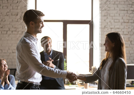 Male team leader handshaking female excited employee congratulat 64660450