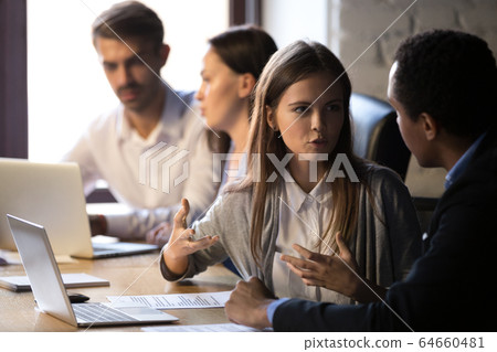 Young female worker speaking to male african colleague explainin Young female worker speaking to male african colleague explainin 64660481