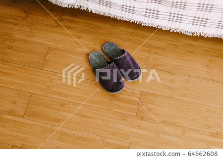 Warm felt purple slippers made of piled sheeps wool, stand on a wooden floor of laminate 64662608