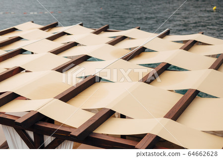Unusual roof closure. The roof of the restaurant on the street by the sea. Fabric roof Unusual roof closure. The roof of the restaurant on the street by the sea. Fabric roof 64662628