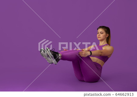 Beautiful young female athlete practicing on purple studio background, monochrome portrait 64662913