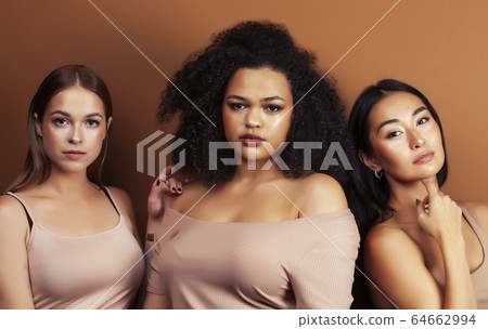 young pretty asian, caucasian, afro woman posing cheerful together on brown background, lifestyle diverse nationality people concept young pretty asian, caucasian, afro woman posing cheerful together on brown background, lifestyle diverse nationality people concept 64662994