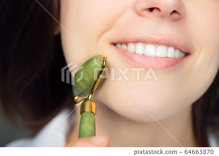 Woman with jade face roller 64663870