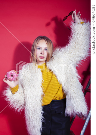 young pretty fashion teenage girl on bright red background holding donut, happy smiling lifestyle people concept 64664183