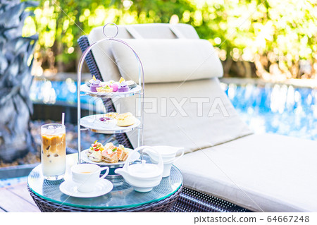 Afternoon tea set with latte coffee and hot tea on table neary chair around swimming pool Afternoon tea set with latte coffee and hot tea on table neary chair around swimming pool 64667248