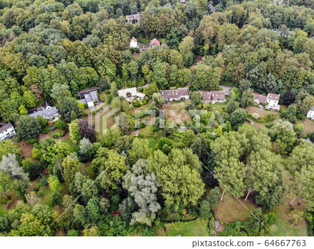 Aerial view of country side area with villas and garden surrounded by forest during green spring season 64667763