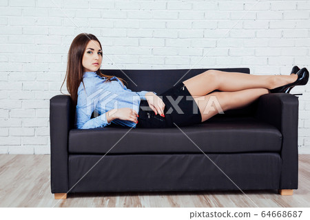 girl lying on a couch and stares into the camera girl lying on a couch and stares into the camera 64668687
