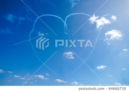 Plane doing acrobatic formation and creating a heart shape in the blue sky.  64668738