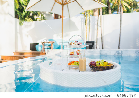 Breakfast and afternoon tea set floating around swimming pool Breakfast and afternoon tea set floating around swimming pool 64669487