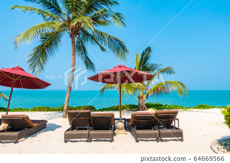 Beautiful tropical beach sea ocean with umbrella and chair around coconut palm tree on blue sky Beautiful tropical beach sea ocean with umbrella and chair around coconut palm tree on blue sky 64669566