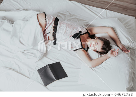 girl in pajamas lying on the bed with a book before bed 64671788