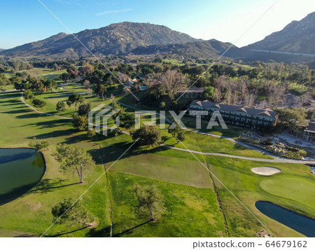 Aerial view of golf course with green field in the valley. Aerial view of golf course with green field in the valley. 64679162