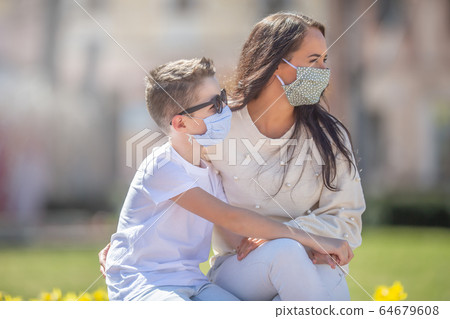 Mother and son with face masks on their faces both Mother and son with face masks on their faces both 64679608