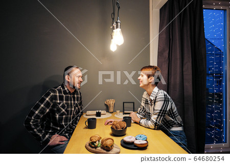 Young married couple in casual clothes, man and woman, sitting at home in the kitchen at the table. Soul communication and home comfort. 64680254