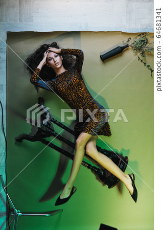 Fashion photo session in the studio. Beautiful woman model. Yellow leopard dress. Studio racks and flashes. Yellow and green background. Fashion photo session in the studio. Beautiful woman model. Yellow leopard dress. Studio racks and flashes. Yellow and green background. 64681341