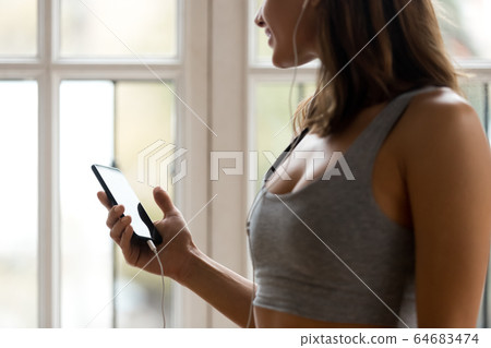 Cropped image young female listens music looking out the window 64683474