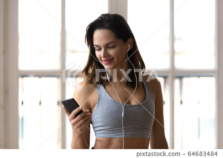 Positive sporty girl using smartphone listening music during wor Positive sporty girl using smartphone listening music during wor 64683484