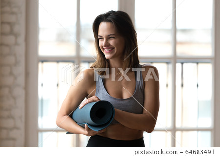 Happy sportswoman holding yoga mat ready for workout Happy sportswoman holding yoga mat ready for workout 64683491