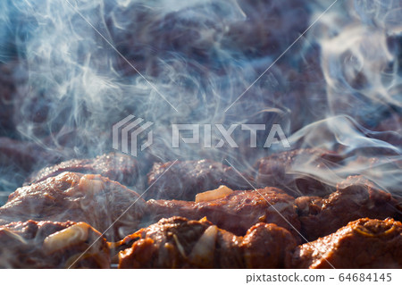 Meat on grill. Morning BBQ. Cooking barbecue on the grill with smoke. Cook fresh marinated meat with onions. Grill marinated barbecue is prepared on the grill on the coals 64684145