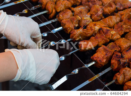 the chef is preparing a barbecue in gloves. We cook meat on the grill outdoors. BBQ 64684294