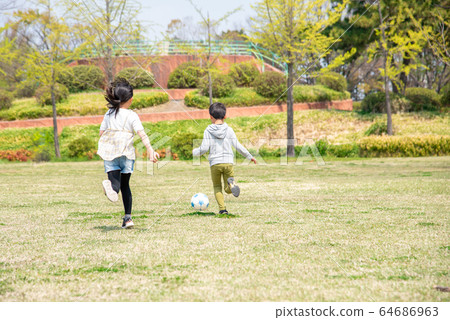 kid playing soccer in the park 64686963