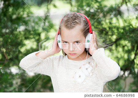Cute little girl enjoying music using headphones Cute little girl enjoying music using headphones 64686998