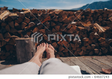 a man is resting after preparing firewood for the winter. feet on the background of dry fallen trees on the ground. Sawmill, woodworking industry, construction, log cutting a man is resting after preparing firewood for the winter. feet on the background of dry fallen trees on the ground. Sawmill, woodworking industry, construction, log cutting 64687243