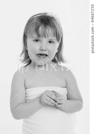 a little girl grimaces against a white background. The child is up to something. Concept of emotions , facial expressions, childhood, sincerity 64687250