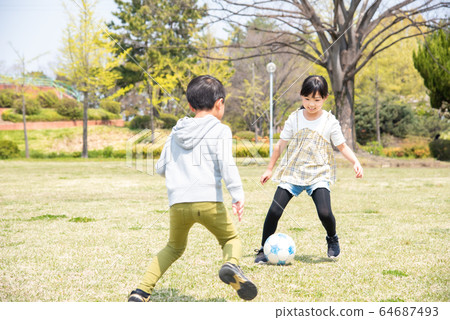 kid playing soccer in the park 64687493