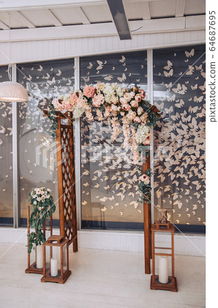 Wedding arch decorated with flowers. Candlesticks and decorative butterflies in the background Wedding arch decorated with flowers. Candlesticks and decorative butterflies in the background 64687695