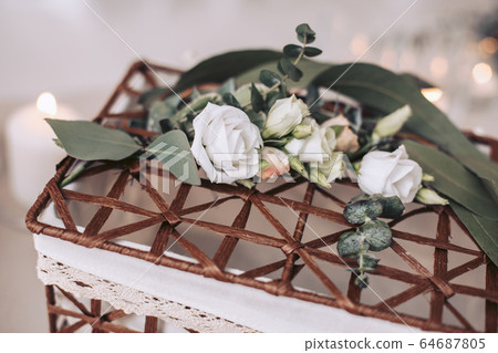 Wicker basket decorated with flowers. Decorative element for the wedding Wicker basket decorated with flowers. Decorative element for the wedding 64687805