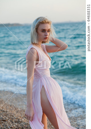 Beautiful fashionable woman in pink dress on the beach by the sea 64688331