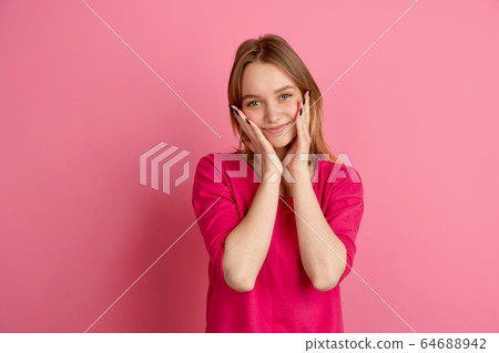 Caucasian young woman's monochrome portrait on pink studio background, emotinal and beautiful 64688942