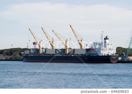 View of a cargo ship loading and unloading on the quay along the canal 64689683