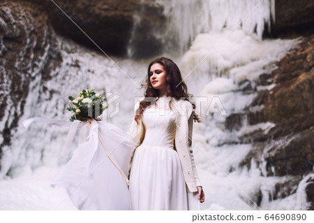Beautiful young girl in a wedding dress against a background of a glacier in the mountains Beautiful young girl in a wedding dress against a background of a glacier in the mountains 64690890