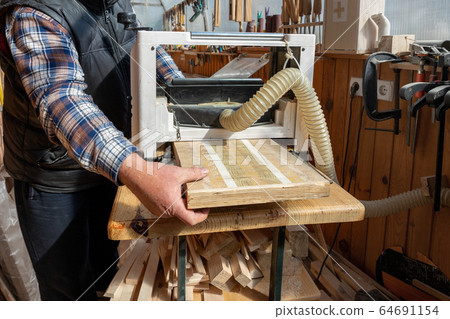 Senior craftsman woodworking at carpentry with lots of modern professional power tools. Man using thicknessing planer machine, clamp joiner, circular saw and other equipment at workshop.hobby concept 64691154