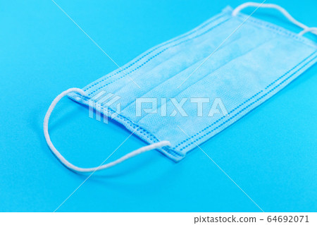 disposable face mask on blue background, respiratory protection 64692071