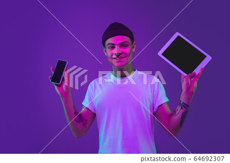 Caucasian man's portrait isolated on purple studio background in neon light Caucasian man's portrait isolated on purple studio background in neon light 64692307