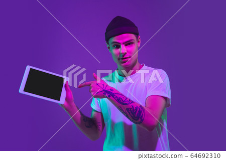 Caucasian man's portrait isolated on purple studio background in neon light 64692310