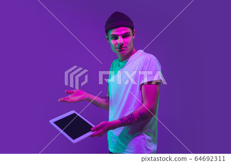 Caucasian man's portrait isolated on purple studio background in neon light Caucasian man's portrait isolated on purple studio background in neon light 64692311