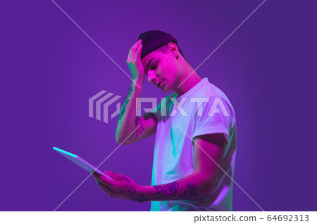 Caucasian man's portrait isolated on purple studio background in neon light 64692313