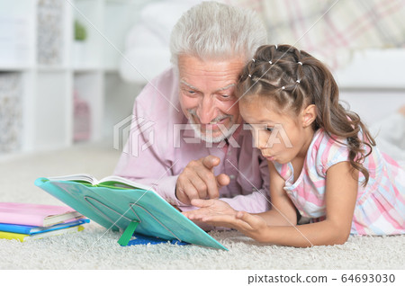 Grandfather reading book with his little granddaughter 64693030
