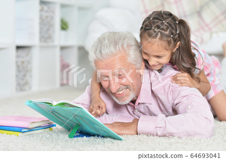 Grandfather reading book with his little granddaughter 64693041